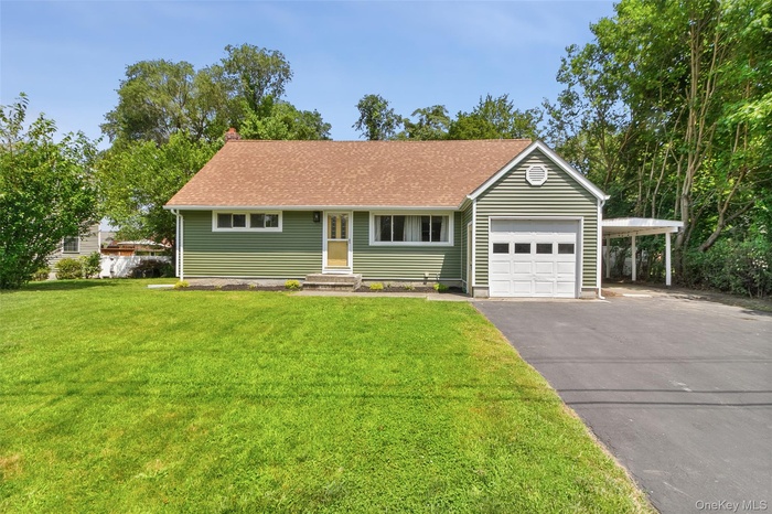 View of front of home with an attached garage, driveway, a front lawn, a chimney, and a carport
