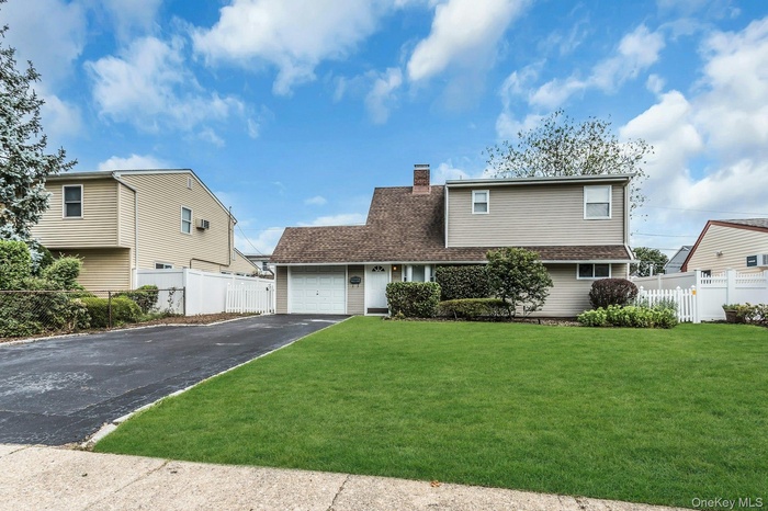 View of front of property featuring driveway, a chimney, and a garage
