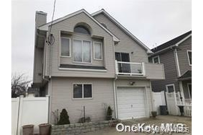 Back of property featuring a balcony, a chimney, and a garage