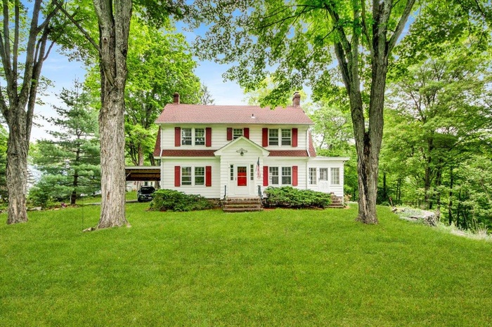 View of front of home with a chimney, a front yard, and a carport