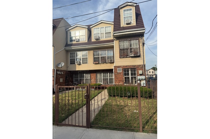 View of front facade featuring brick siding, a fenced front yard, and a gate