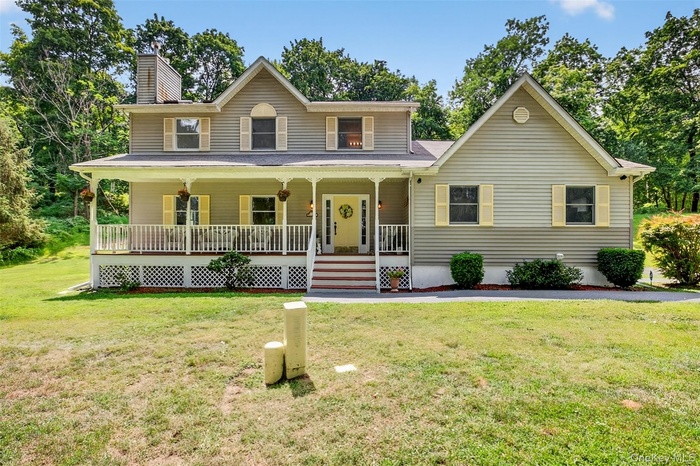 View of front of home with a porch, a front lawn, and a chimney