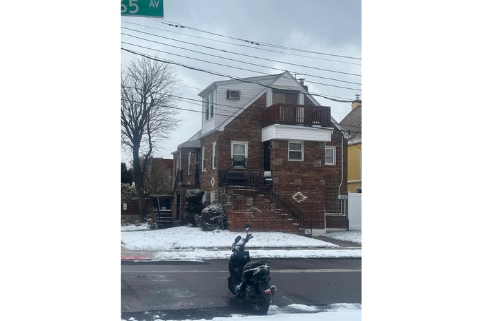 View of front of property with brick siding and a balcony