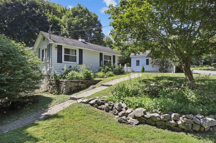 View of front facade featuring a front lawn and a chimney