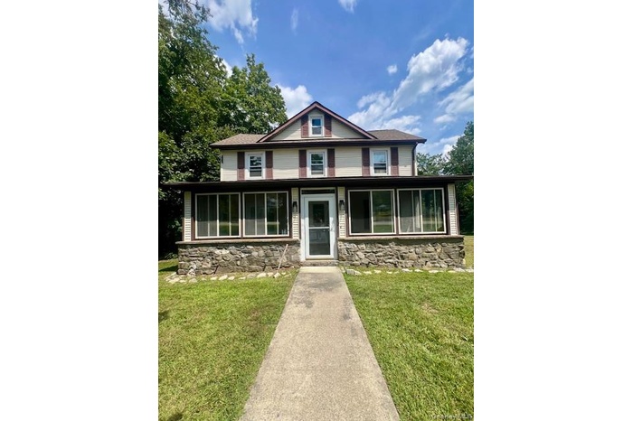 View of front of property featuring stone siding and a front yard
