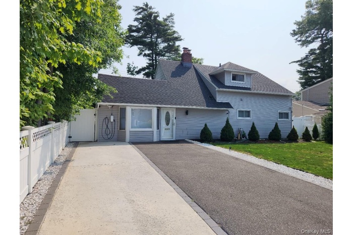 View of front of home featuring a shingled roof, driveway, and a chimney