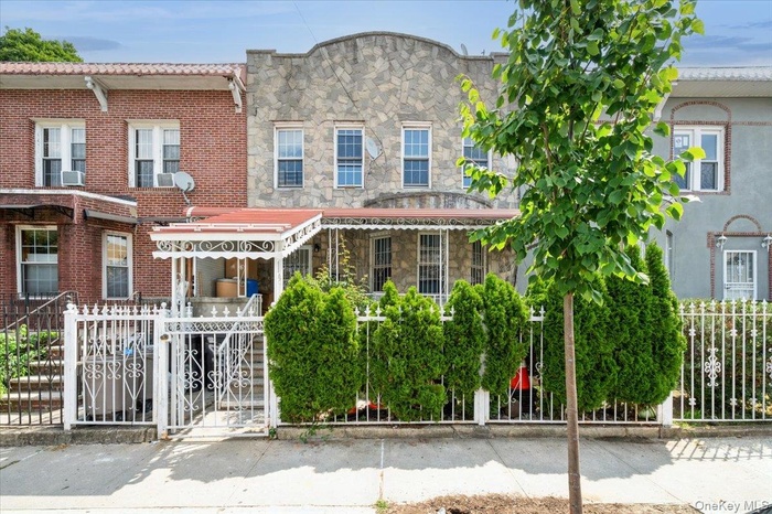 View of front facade with a fenced front yard, stone siding, and a gate