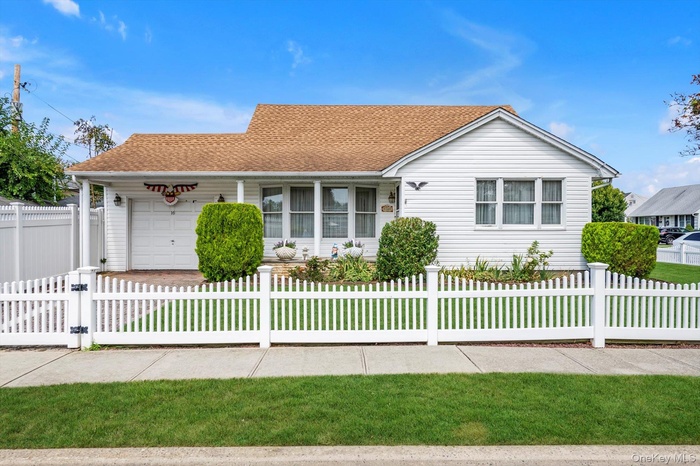 View of front of property featuring a shingled roof, covered porch, an attached garage, a fenced front yard, and concrete driveway