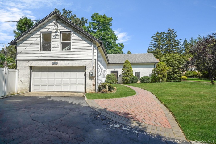 View of front of home featuring a garage, a front lawn, driveway, and brick siding