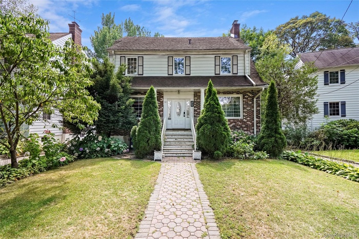 Traditional-style home featuring a front yard, brick siding, and a chimney