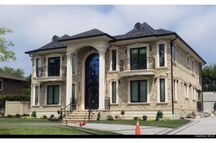 View of front of house featuring a balcony and brick siding