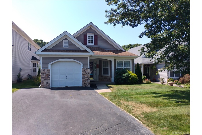 Craftsman inspired home featuring asphalt driveway, stone siding, a garage, and a front lawn