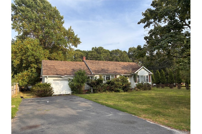 Single story home featuring a garage, asphalt driveway, and a chimney