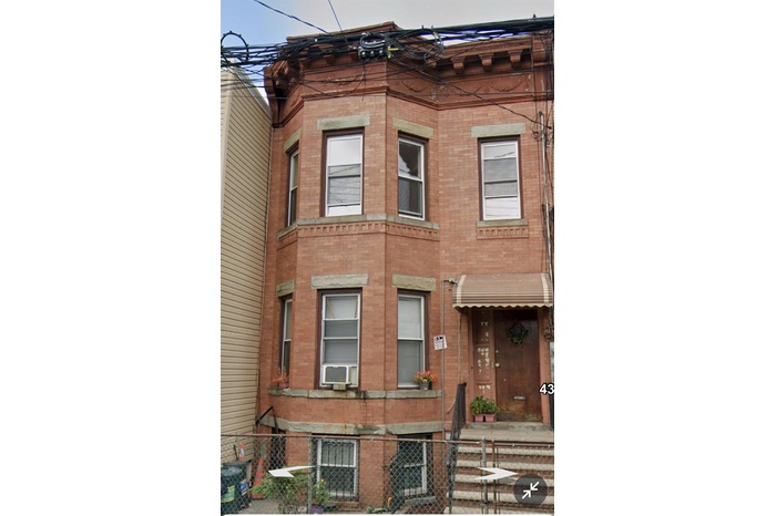 View of front of house featuring brick siding, cooling unit, and a fenced front yard