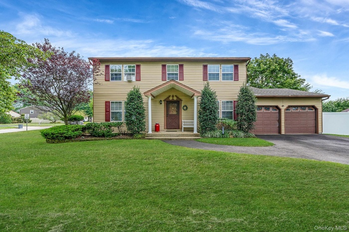 Colonial house with asphalt driveway, an attached garage, and a front yard