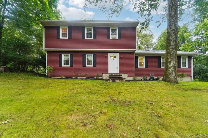 Colonial-style house featuring a front lawn and entry steps