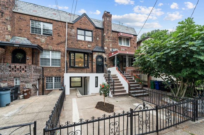 View of front of home with a high end roof, a fenced front yard, brick siding, and a balcony