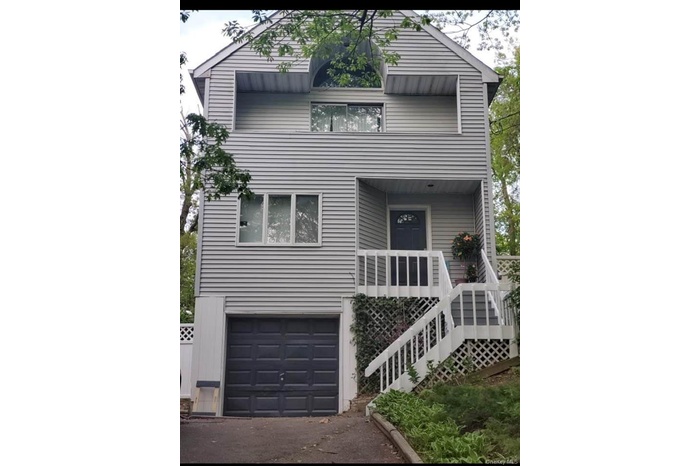 View of front facade with an attached garage, driveway, and stairway
