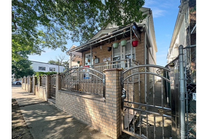 View of front of home featuring a gate, a fenced front yard, brick siding, and covered porch
