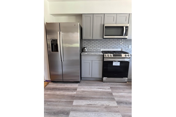 Kitchen featuring fridge, stove, gray cabinetry, and backsplash