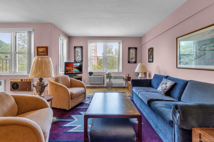 Living room with plenty of natural light, radiator, wood finished floors, and a wall mounted air conditioner
