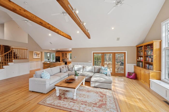 Living area with light wood-type flooring, ceiling fan, stairway, and beam ceiling