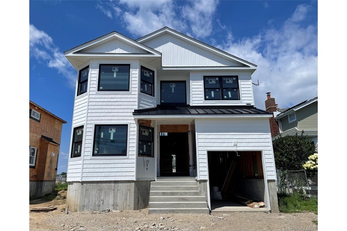 View of front of property with a standing seam roof, an attached garage, a metal roof, and covered porch