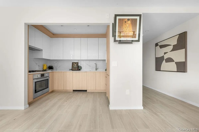 Kitchen with light brown cabinets, oven, modern cabinets, and light wood-type flooring