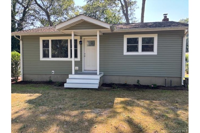 View of front of property featuring a front yard, a chimney, and roof with shingles