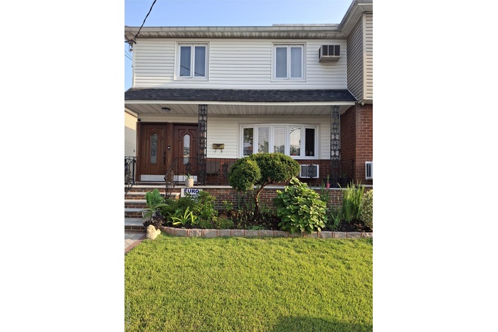 View of front of house featuring a porch, a front lawn, and brick siding
