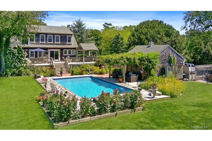 View of pool featuring a lawn, a patio, a wooden deck, and stairs