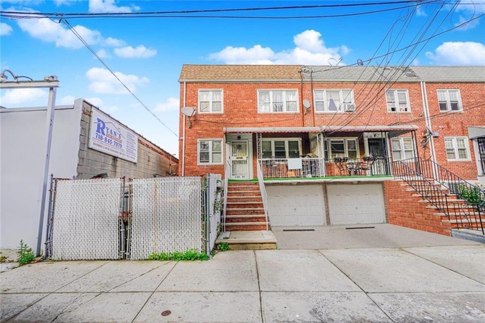 View of front facade featuring stairway, driveway, an attached garage, brick siding, and a gate