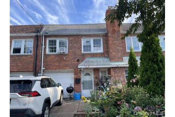 Traditional-style home featuring driveway, brick siding, a garage, and a chimney
