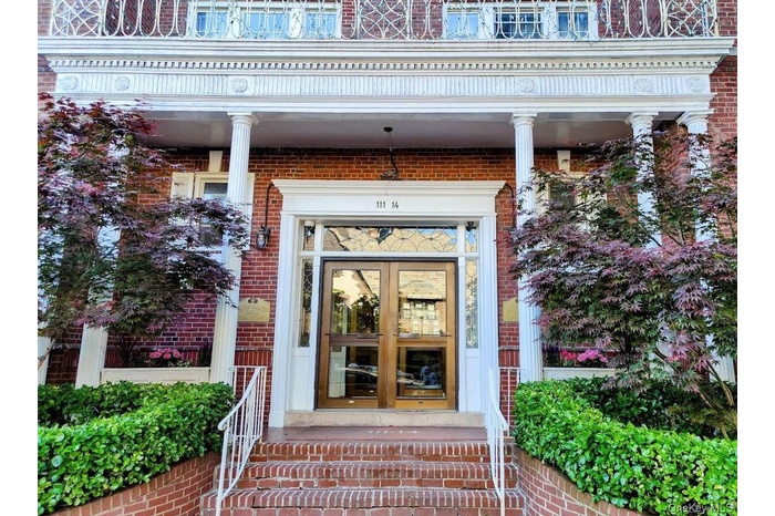 Property entrance featuring french doors, brick siding, and covered porch