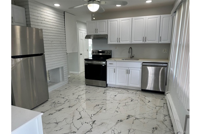Kitchen with appliances with stainless steel finishes, a baseboard heating unit, recessed lighting, a ceiling fan, and light countertops