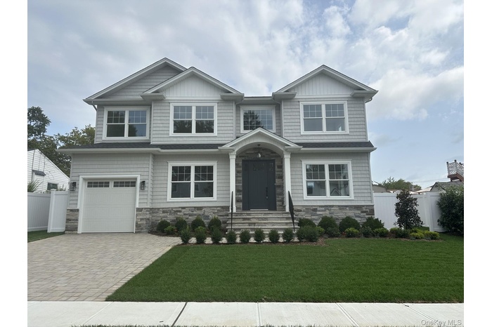 Craftsman inspired home featuring stone siding, an attached garage, and decorative driveway