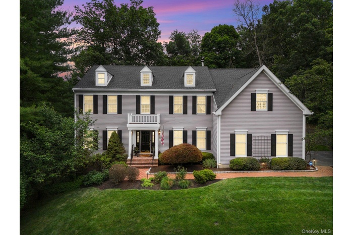 Colonial-style house featuring a yard, roof with shingles, and a balcony