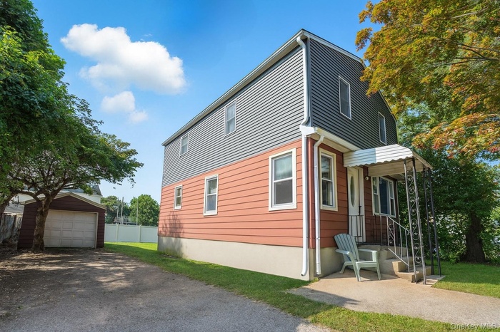 View of side of property with an outdoor structure, driveway, and a garage