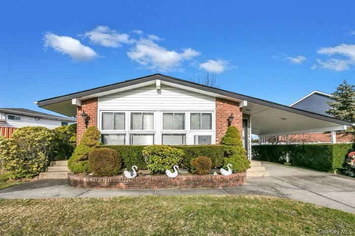 View of front of house with brick siding, driveway, a carport, and a front yard