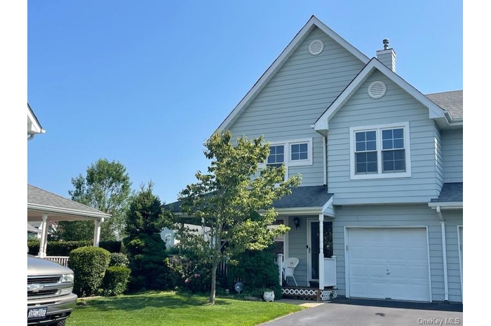 View of front of home with a garage, a chimney, asphalt driveway, a front yard, and a shingled roof
