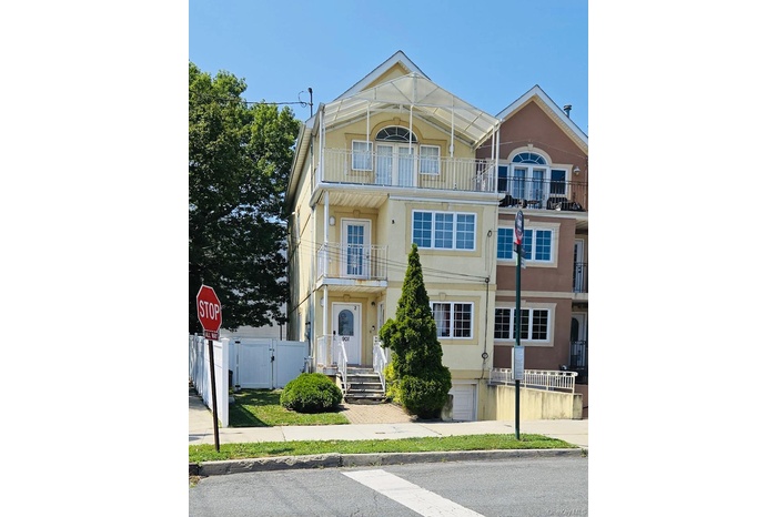 View of front of home featuring a balcony, stucco siding, and a gate