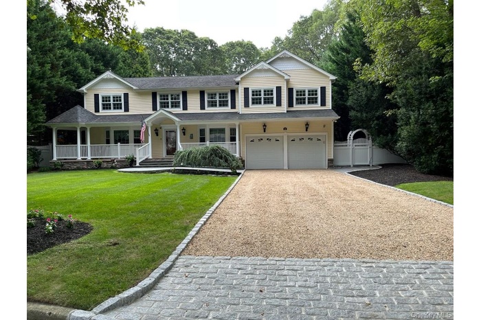 Traditional-style home with a porch, driveway, a gate, and a garage