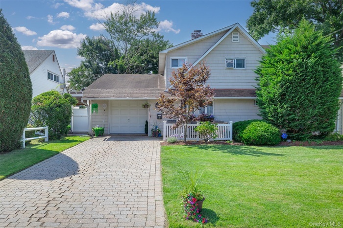Traditional-style house with a garage, decorative driveway, and a chimney