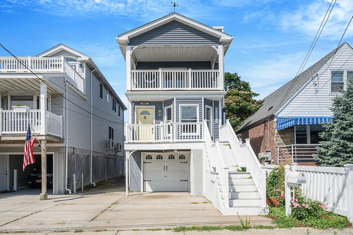 Beach home with an attached garage, stairs, and driveway