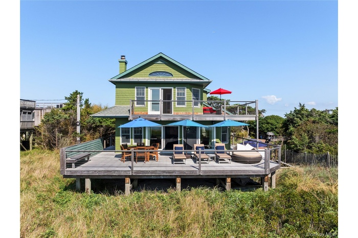 Rear view of house with a deck, a chimney, outdoor dining space, and a balcony