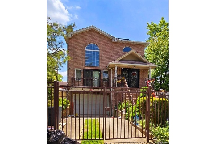 View of front of property featuring brick siding, a balcony, and a gate