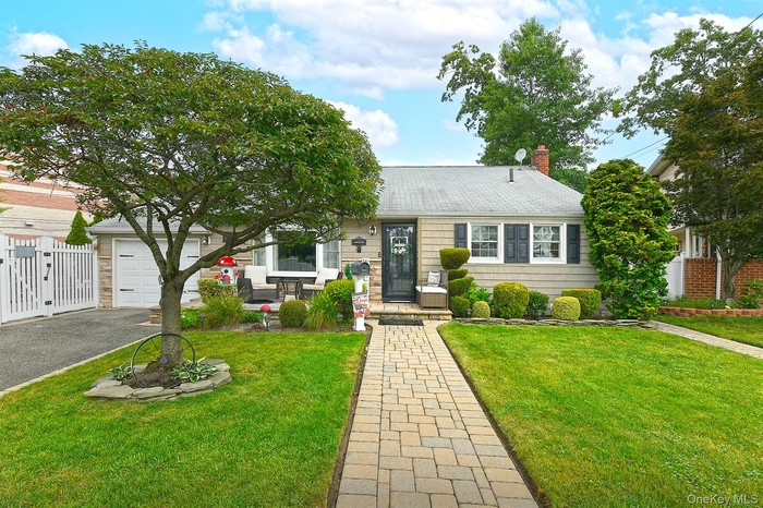 View of front facade with roof with shingles, a chimney, a garage, and driveway