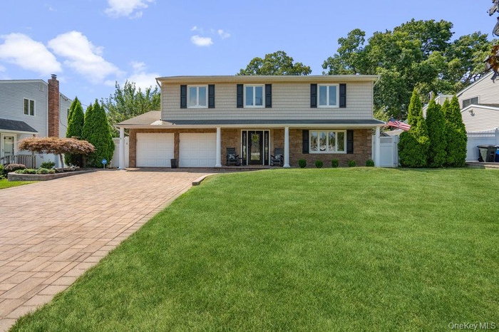 Traditional home featuring covered porch, a front lawn, and decorative driveway