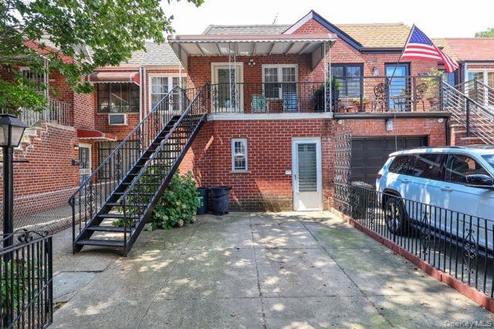 View of front facade featuring concrete driveway, a garage, stairway, and brick siding