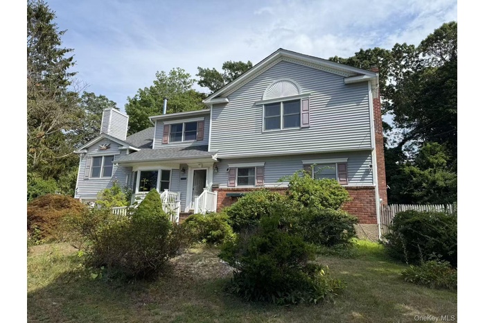 View of front facade featuring brick siding and a chimney